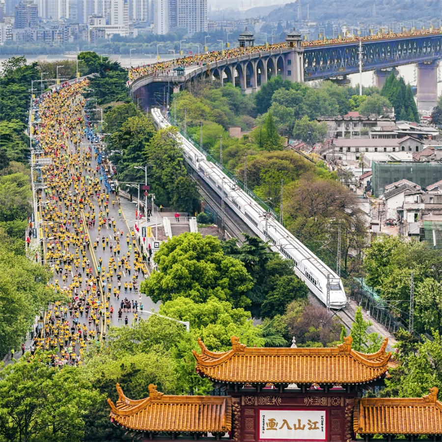 2019年4月14日，武汉马拉松举行。选手们经过武汉长江大桥，与动车同行，与黄鹤楼同框。 姜涛 摄